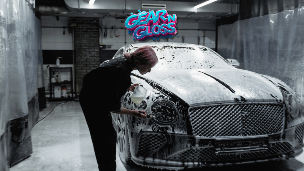 Frau wäscht schwarzes Auto mit Wasser und Schaum in einer Garage.